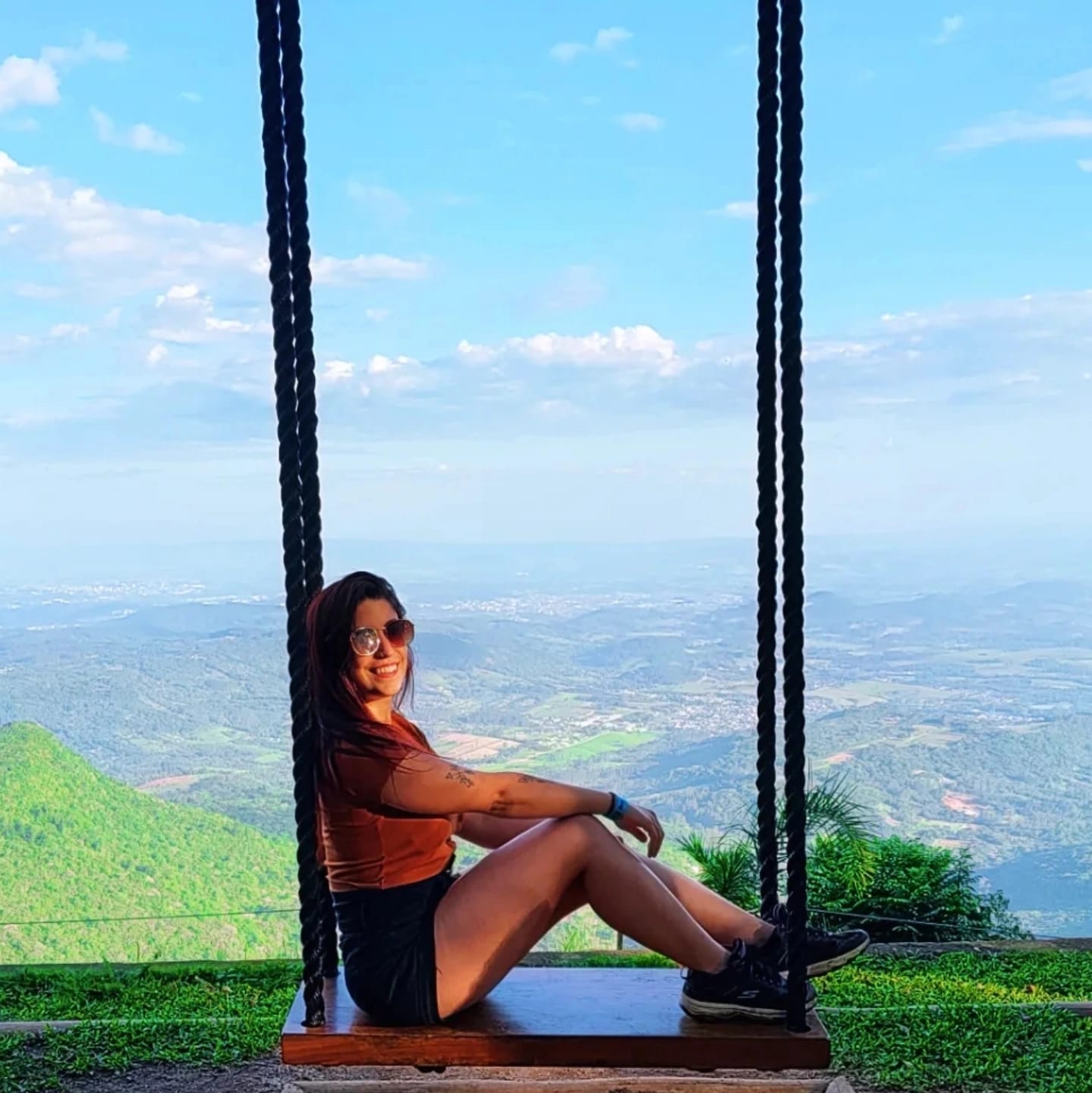 Laíza Cambraia sentada em um balanço com vista para as montanhas